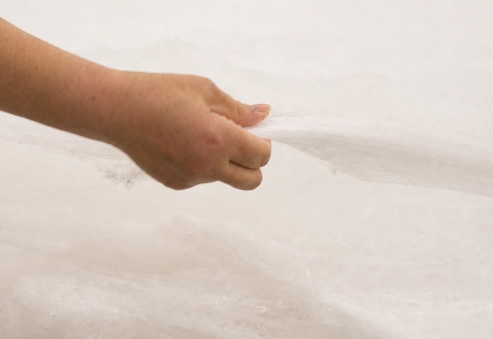 Long silk fibres being opened by hand during duvet making